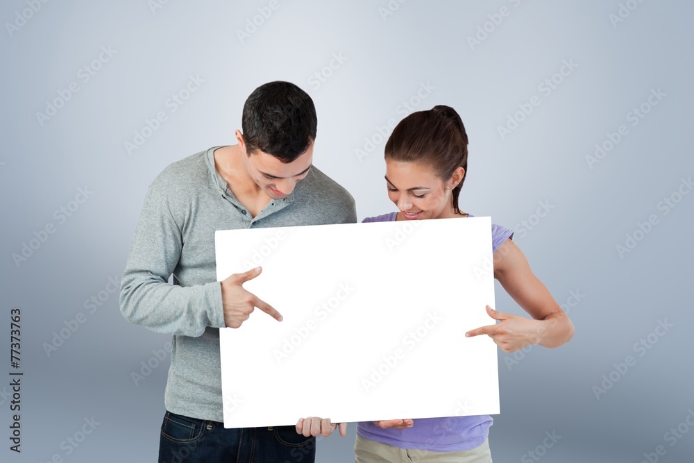 Young couple pointing at banner they are presenting Young couple pointing at banner they are presenting