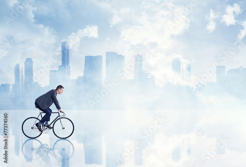 Businessman on a bicycle on megalopolis background © SFIO CRACHO