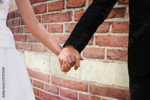 Mid section of newlywed couple holding hands