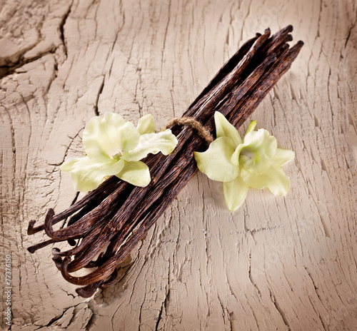 Bunch of vanilla sticks and flowers on old wood.