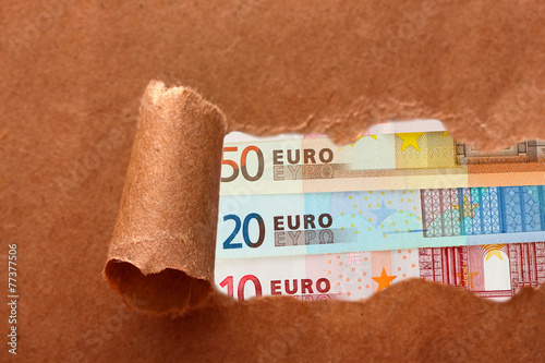 Euro banknotes through torn craft paper