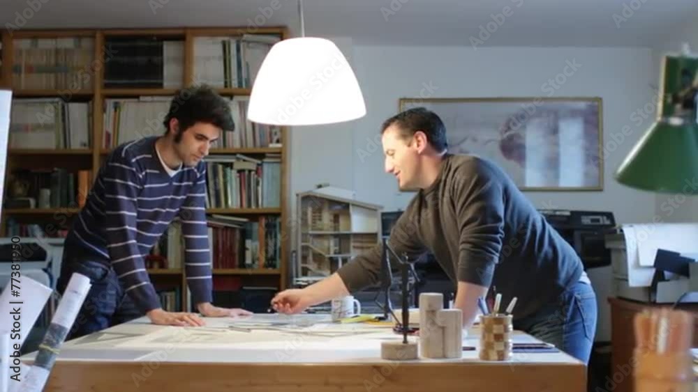 Two architects examining a plan in an office (dolly) Two architects examining a plan in an office (dolly)
