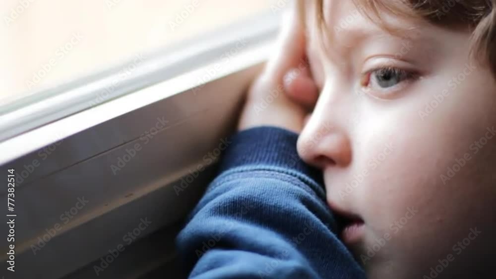 beautiful child bored and sad looking through window