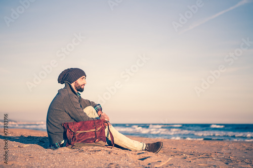 Man sitting at the beach at sunset in winter © photopitu