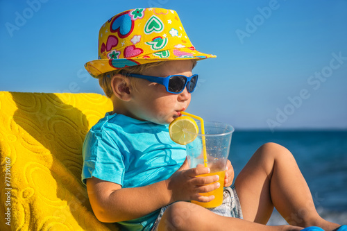 kid drinks juice against sea