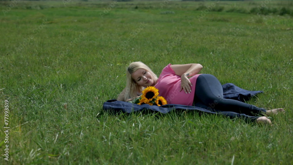 Woman stroking her stomach while resting on the blanket Woman stroking her stomach while resting on the blanket