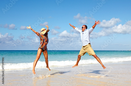 Happy couple jumping on the beach.