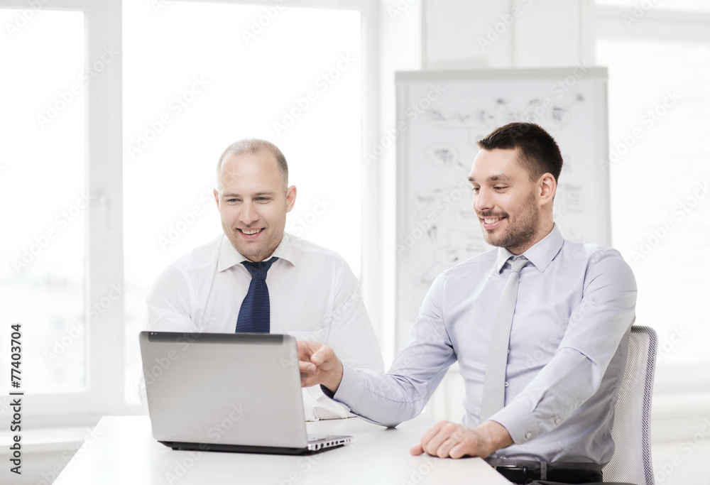 two smiling businessmen with laptop in office two smiling businessmen with laptop in office