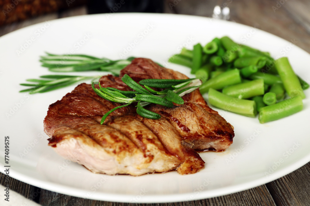 Steak with herbs on plate on wooden table