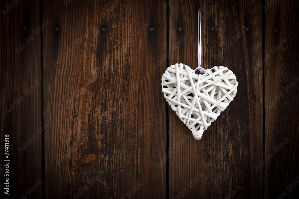 White wicker heart on wooden background White wicker heart on wooden background