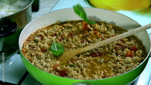 Adding some green spices onto the boiling soya meal in the pan  photo