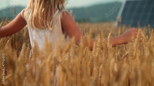 Little girl on a golden field with solar panels in the back photo