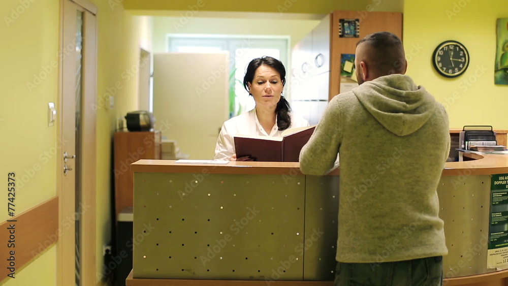 Patient and nurse with tablet conversing at hospital reception d