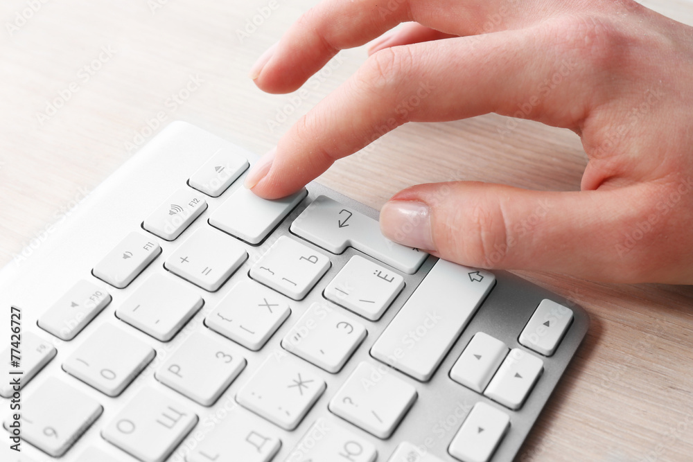 Female hand with keyboard on wooden desktop background Female hand with keyboard on wooden desktop background