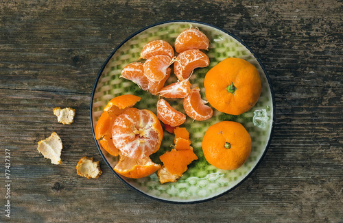 A plate of fresh ripe juicy mandarins over a rough wood backgrou