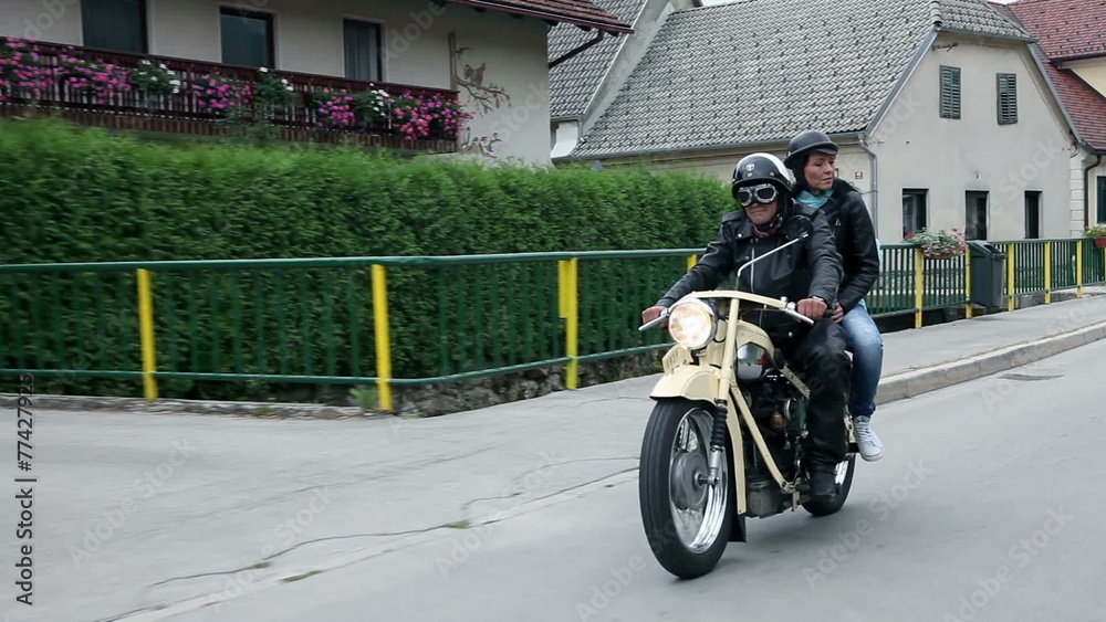 Couple on retro motorcycle driving through small town Couple on retro motorcycle driving through small town
