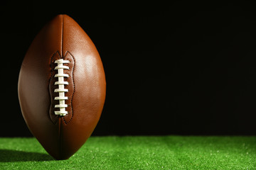 American football on green grass, on black background