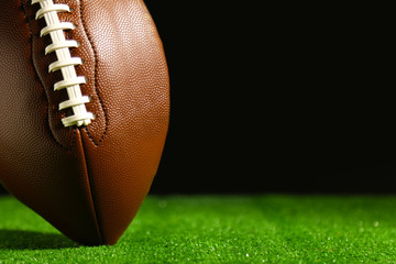 American football on green grass, on black background