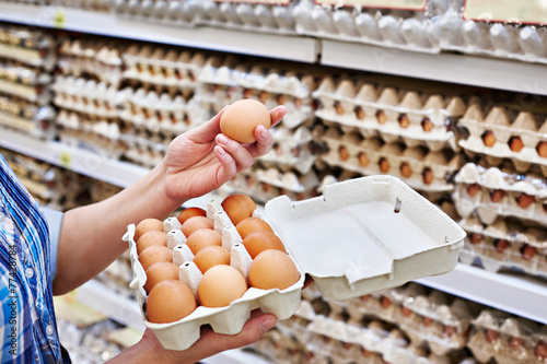 In hands of woman packing eggs in supermarket