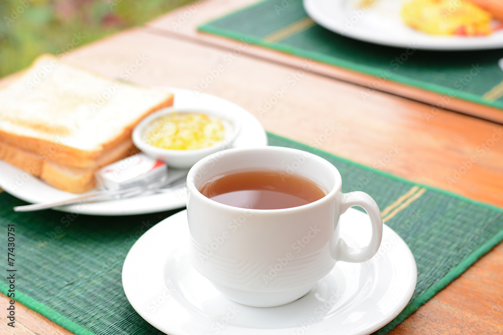 Hot tea in white cup with sliced bread on green mat Hot tea in white cup with sliced bread on green mat