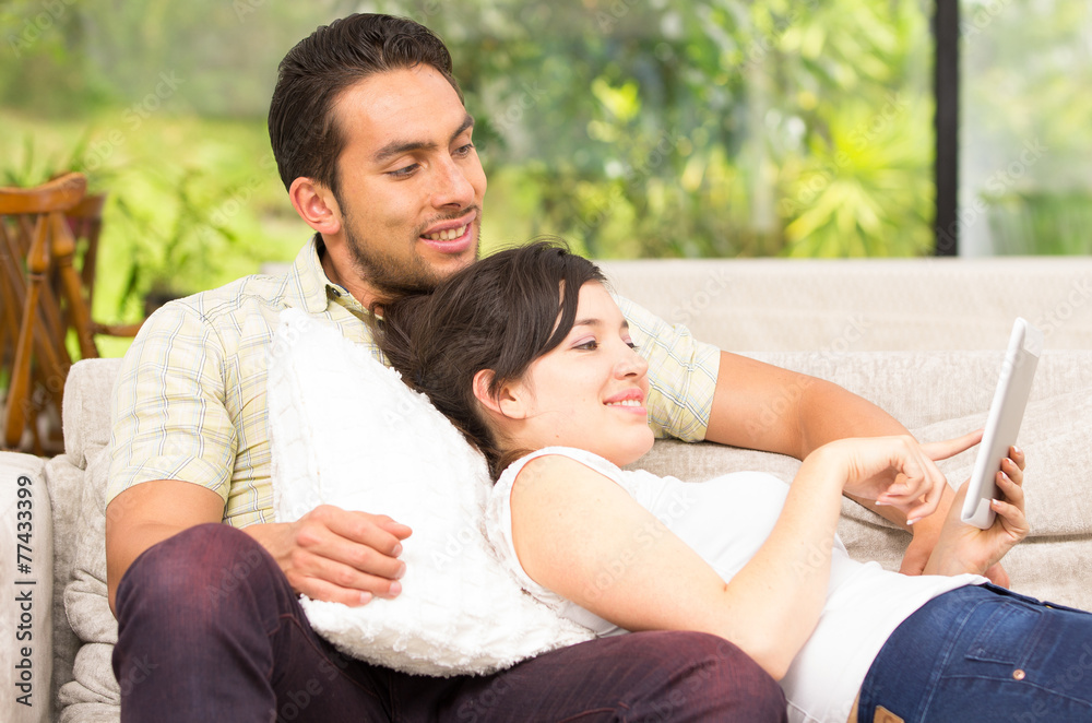 young attractive couple relaxing in the sofa using tablet young attractive couple relaxing in the sofa using tablet