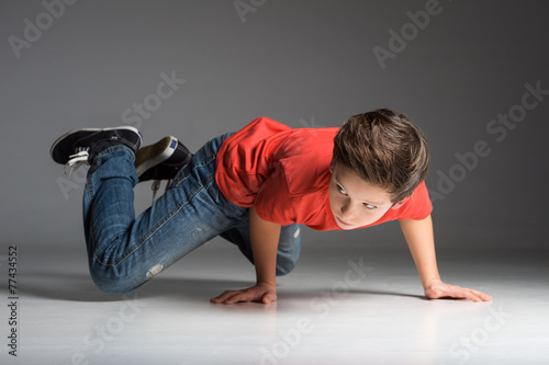 little break dancer showing his skills on grey background.