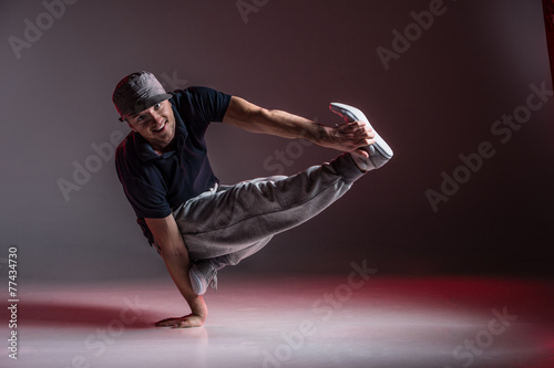 young break dancer showing his skills on grey background.