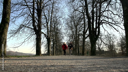 Two females run straight towads the camera in the winter shot photo