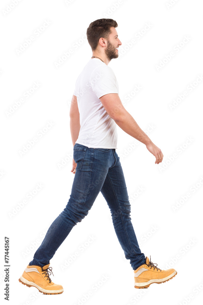 Young man walking in jeans and white t-shirt - obrazy, fototapety, plakaty 