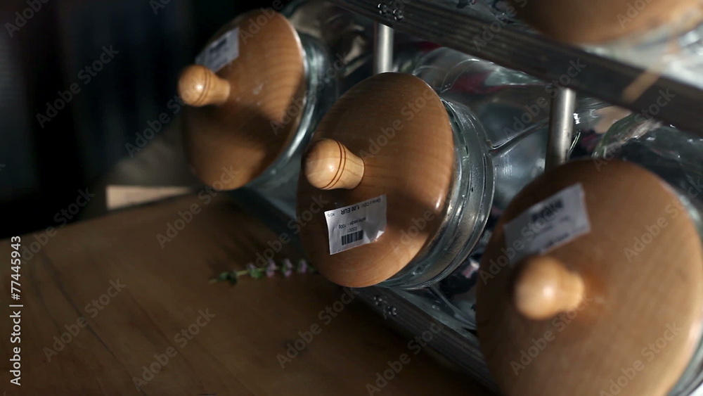 Close up shot of a seller who is taking candies out of the big glass jar