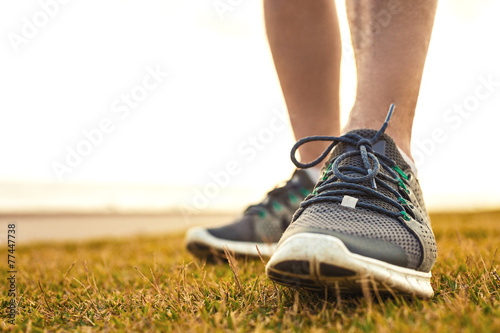 sportsman's legs standing on the grass in running shoes close up