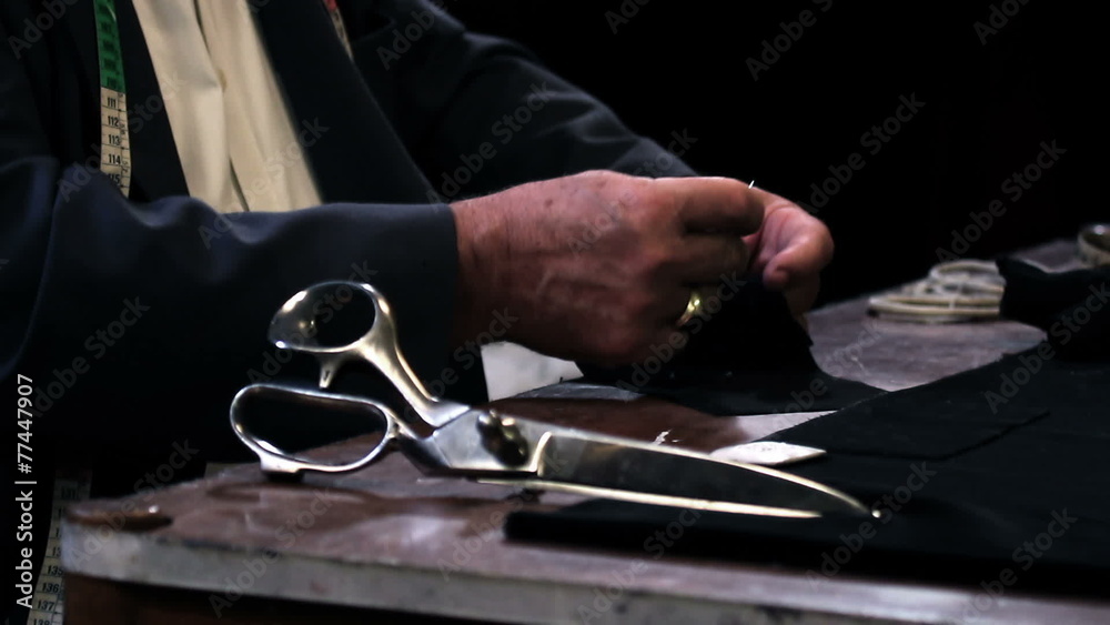 Close up shot of a tailor sewing a button Close up shot of a tailor sewing a button