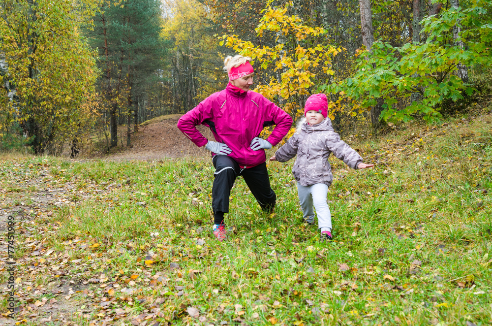 Fototapeta premium Woman with girl doing aerobics in the autumn park