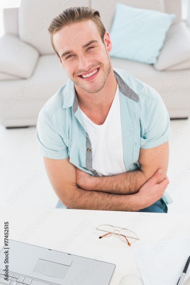 Smiling businessman with arms crossed at his desk