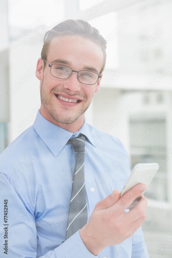 Smiling businessman holding mobile looking at camera Smiling businessman holding mobile looking at camera