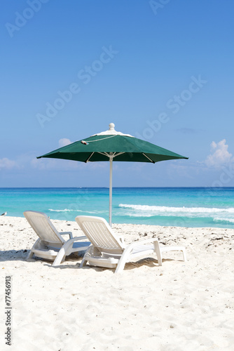 Pair of sun loungers and umbrella on a tropical beach in Cancun 