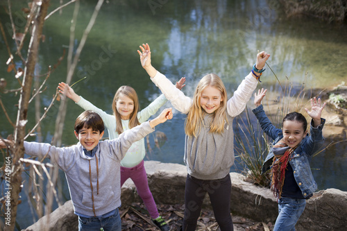 Niños junto a río levantando los brazos