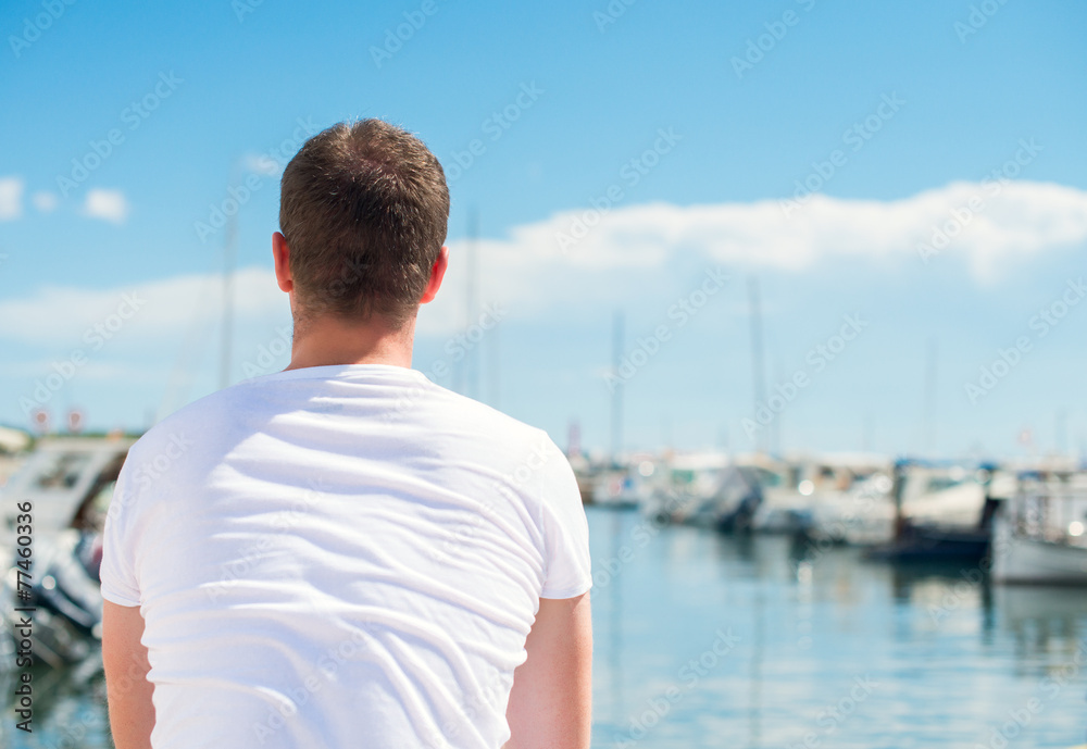 Man looking on pier with yachts.