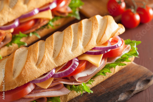 long baguette sandwich with ham cheese tomato and lettuce