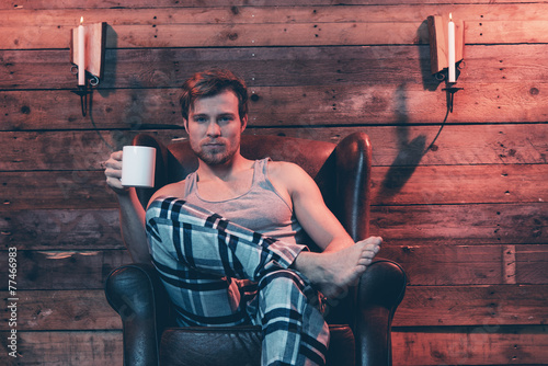 Man with blonde hair wearing winter sleepwear. Sitting in leathe photo