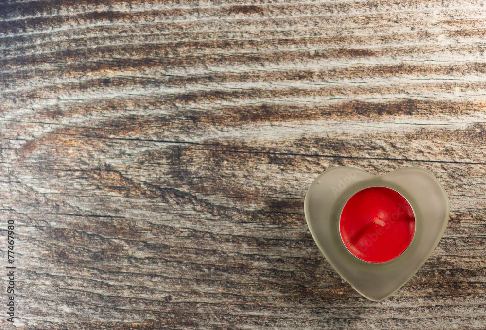 Red candle fire in heart on wooden background