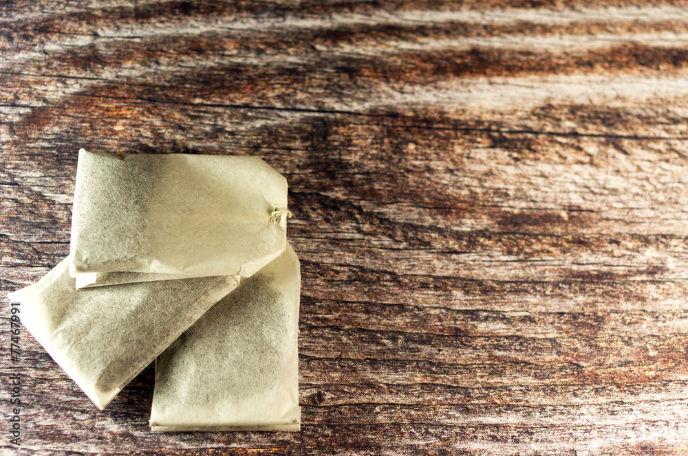 Three tea bags on wooden background