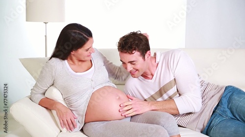 young father posing his ear on his wife paunch