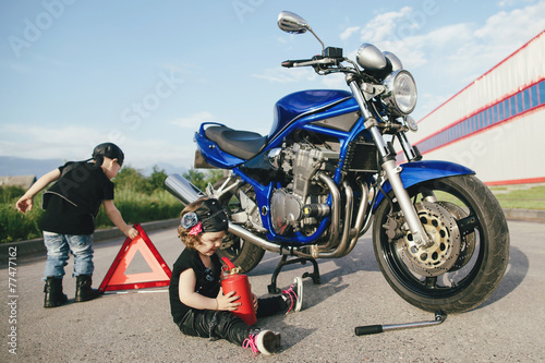 Fototapeta Naklejka Na Ścianę i Meble -  little biker repairs motorcycle on road