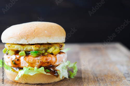 Homemade fish burger with salmon, avocado and pineapple.Close up