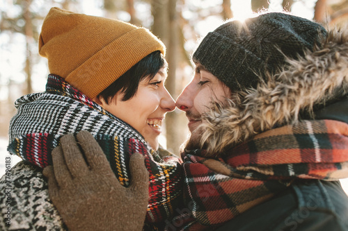 Young hipster couple having fun in winter forest