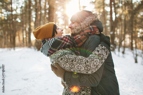 Young hipster couple hugging each other in winter forest