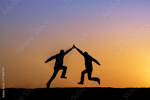 Two man holding for hands and jumping.