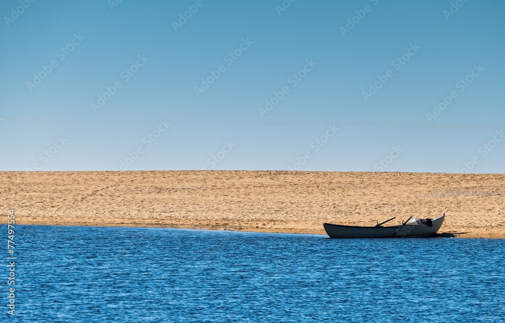 Obraz premium Solo Rowboat Moored on Sandy Beach
