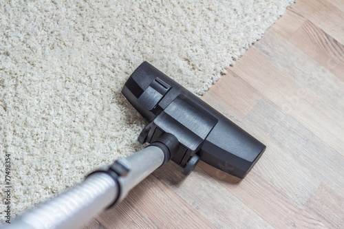 Vacuum cleaner being used to vacuum a carpet